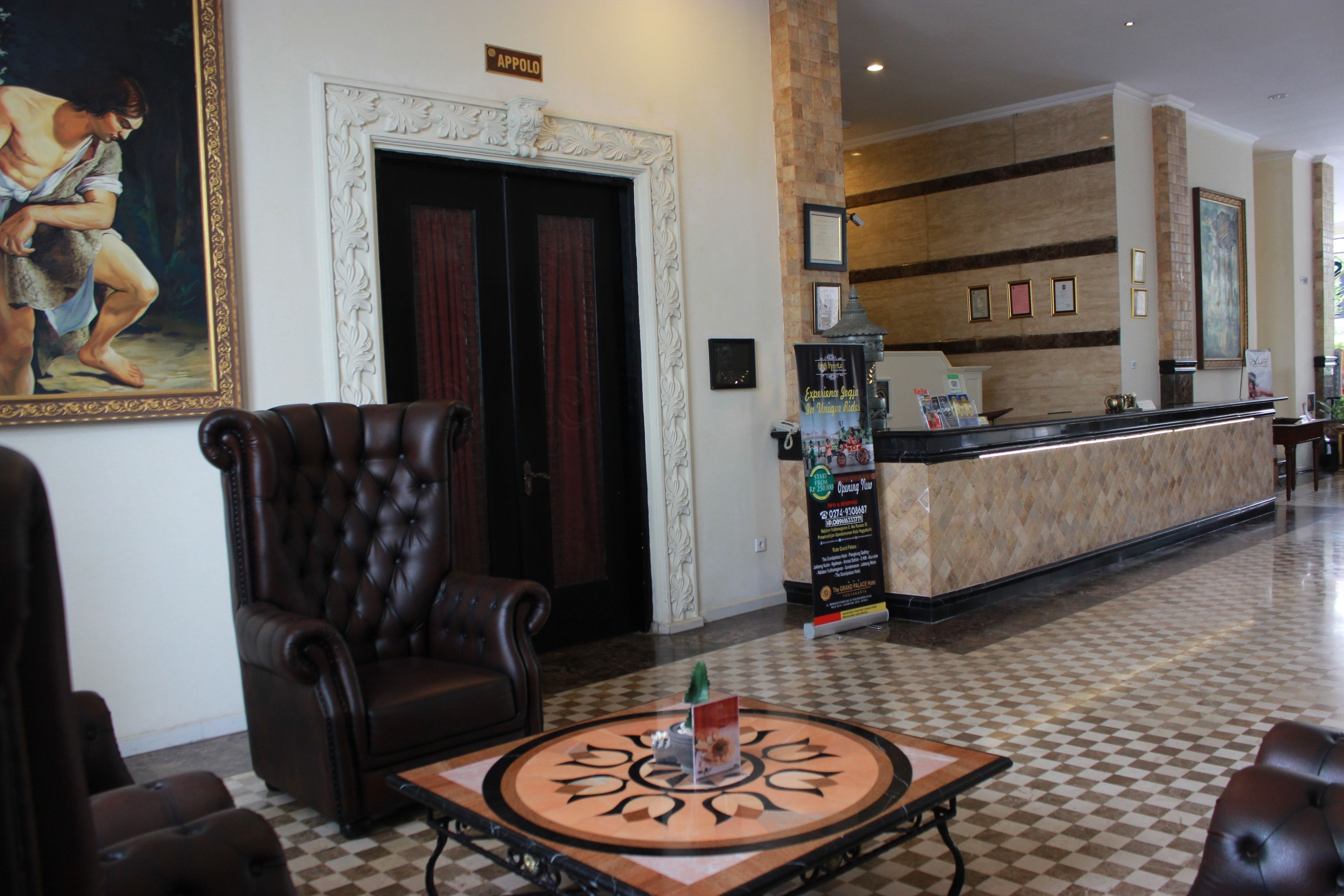 A lobby with a reception desk, a large framed painting, a dark leather armchair, and a checkered floor.