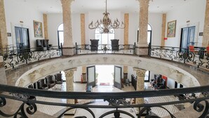 A grand lobby with a central chandelier, ornate columns, and a checkered floor. - The GRAND PALACE Hotel - YOGYAKARTA (Yogyakarta)
