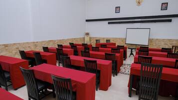 A conference room with multiple tables and chairs, a whiteboard, and a projector screen.