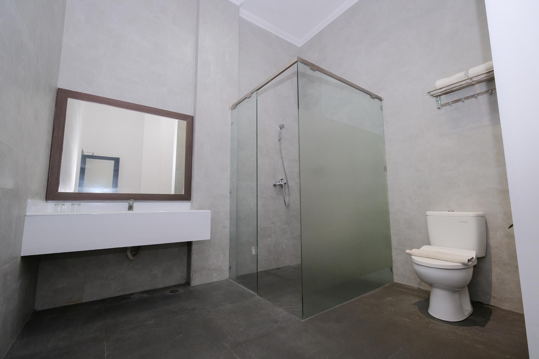 Un baño moderno con ducha acristalada, inodoro blanco y un espejo grande sobre un lavamanos blanco.