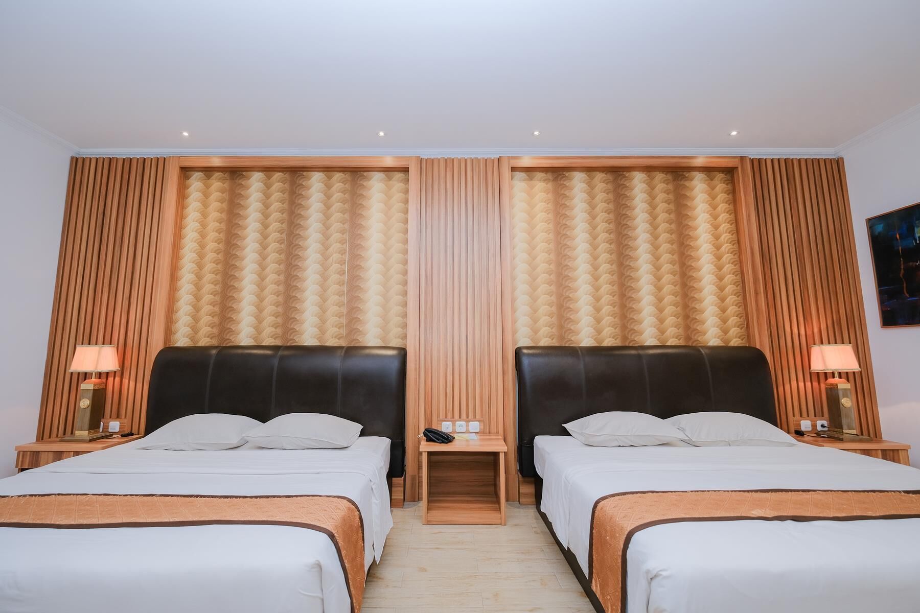 A hotel room with two beds, wooden headboards, and a large mirror.