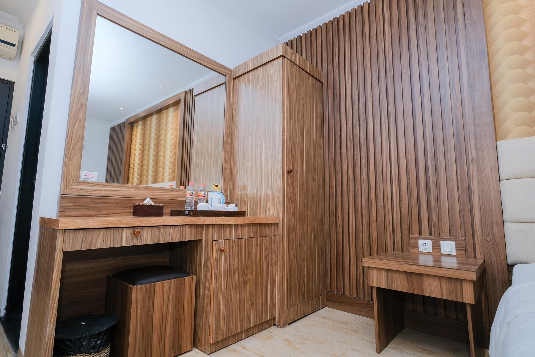 A modern bathroom with a wooden vanity, a mirror, and a small bedside table.