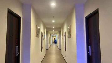 A long, narrow hotel corridor with doors on both sides, leading to rooms.
