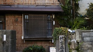 Un edificio japonés tradicional con fachada de madera, una puerta de piedra y un cartel.