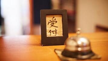 A framed calligraphy piece with Japanese characters on a wooden table, accompanied by a traditional bell.
