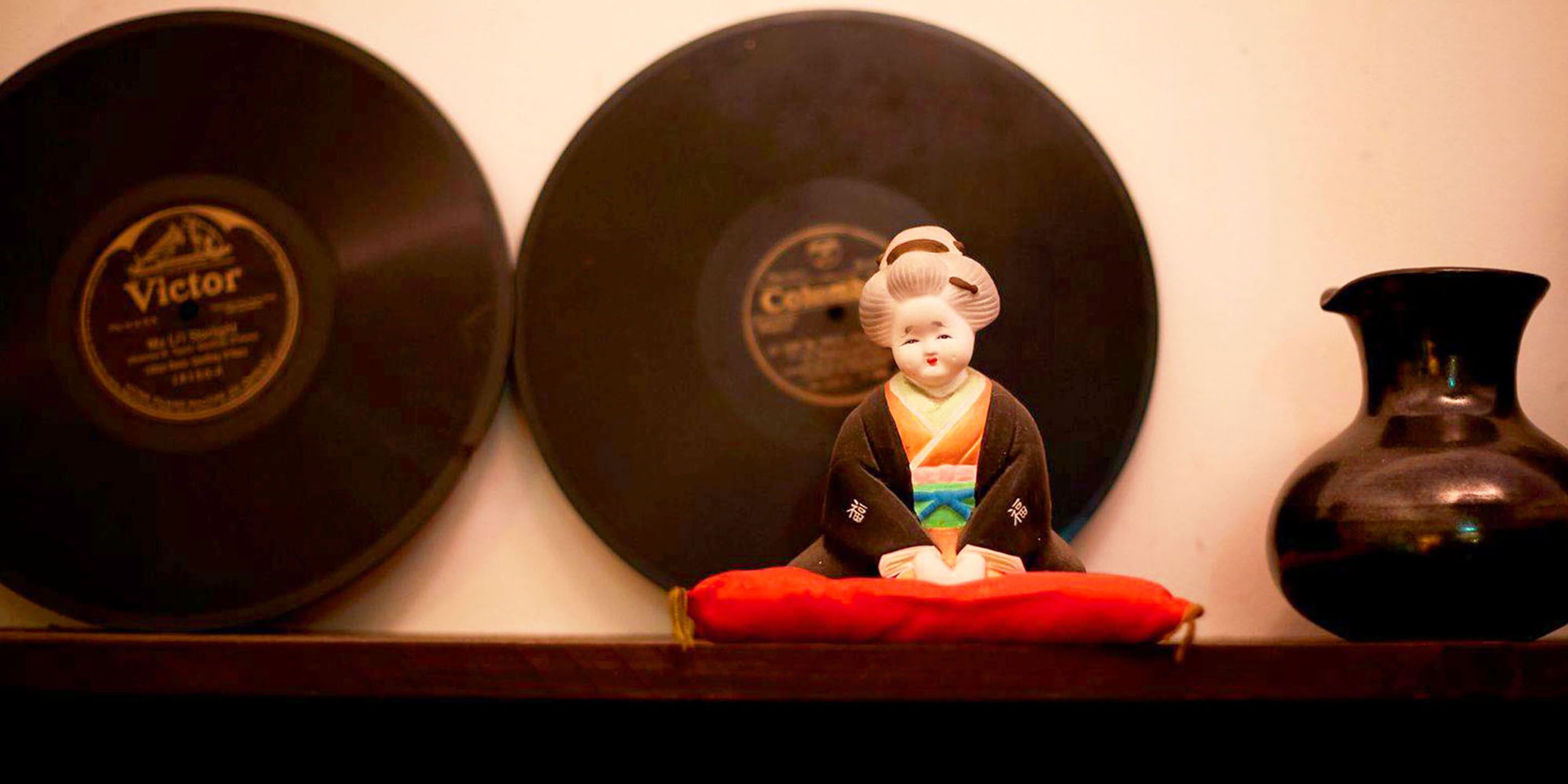 A shelf with vinyl records and a decorative figure.
