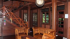 A wooden interior with a staircase, wooden furniture, and large windows. - Villa Del Porto (Langkawi)