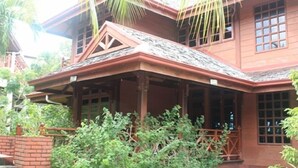 A two-story wooden house with a porch, surrounded by greenery. - Villa Del Porto (Langkawi)