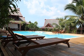 Eine Holzterrasse mit Liegestühlen und einem Swimmingpool.