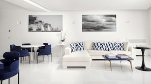 A modern living room with a white sofa, blue chairs, a coffee table, and two wall-mounted paintings.