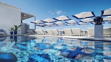 A poolside area with lounge chairs and umbrellas, a clear blue sky, and a modern building facade.