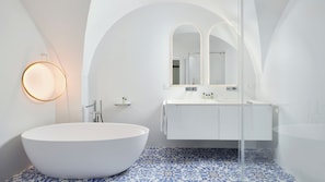 A modern bathroom with a freestanding bathtub, a large mirror, and a white vanity.
