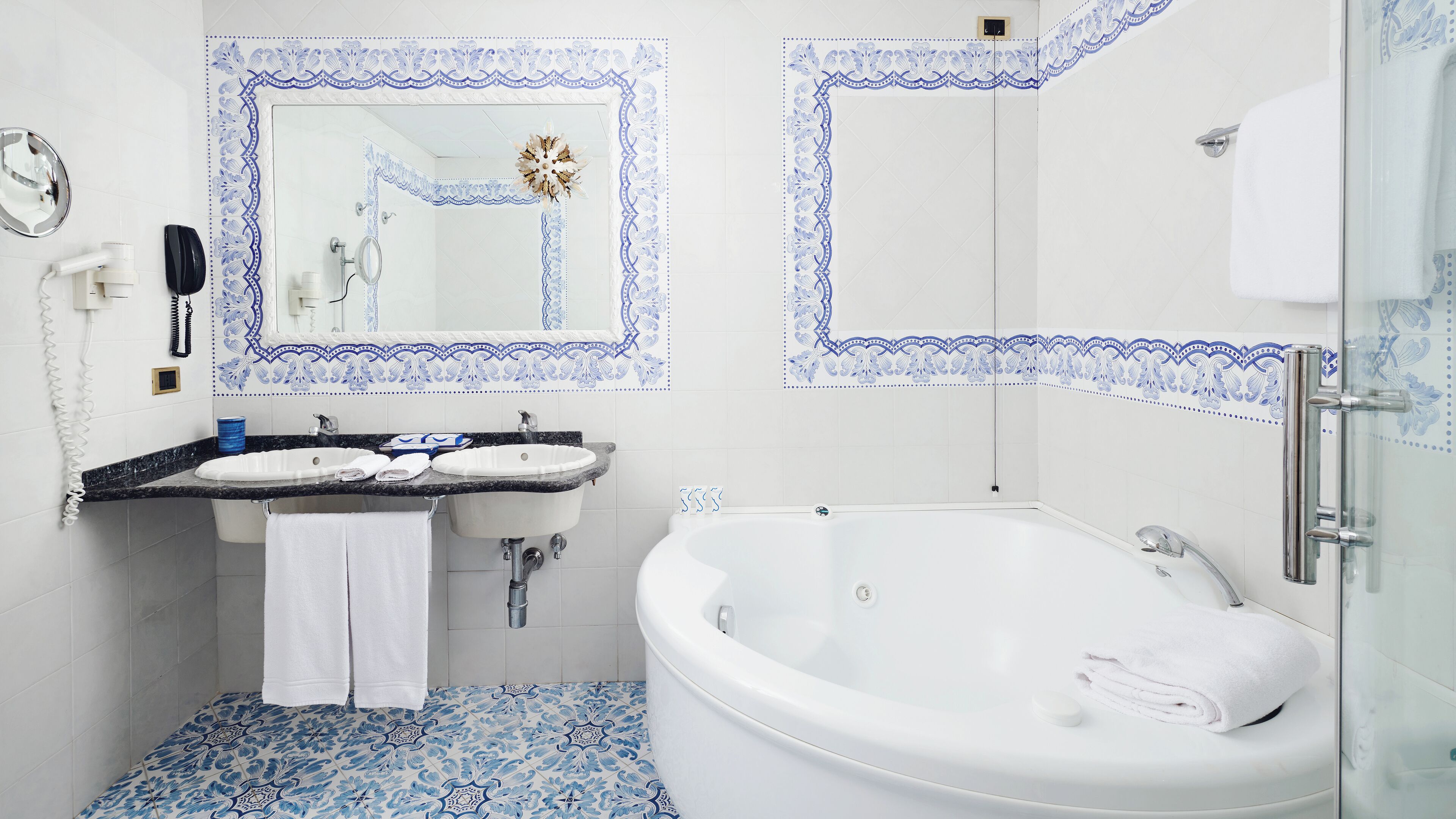 Un baño con una bañera blanca, dos lavamanos y un espejo.