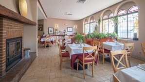 A restaurant with brick fireplace, wooden tables, and potted plants. - Hotel Vivar (Grinon)