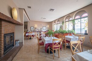 Un restaurante con chimenea de ladrillo, mesas de madera y plantas en macetas.