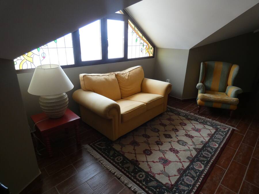 Un salon chaleureux avec un canapé, un tapis à motifs, une lampe et un fauteuil.