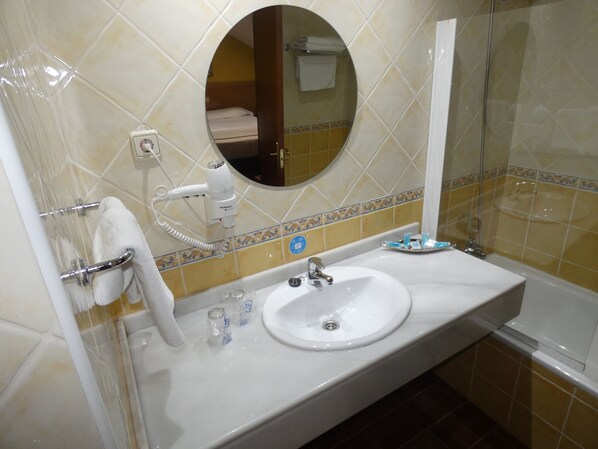 A bathroom with a white sink, a mirror, a hairdryer, and a shower. - Hotel Vivar (Grinon)