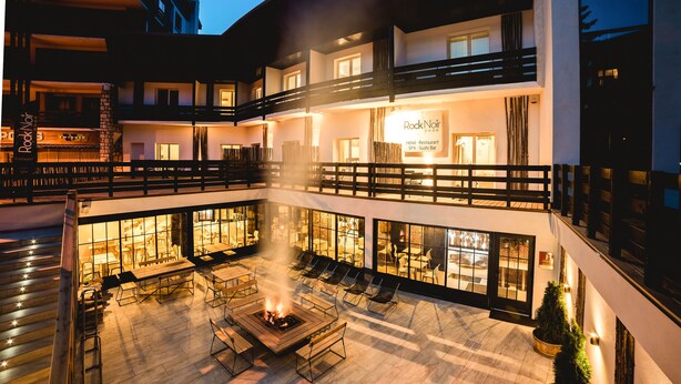 A multi-story hotel with outdoor seating and a fire pit. - Rock Noir Hôtel & Spa (La Salle-les-Alpes)