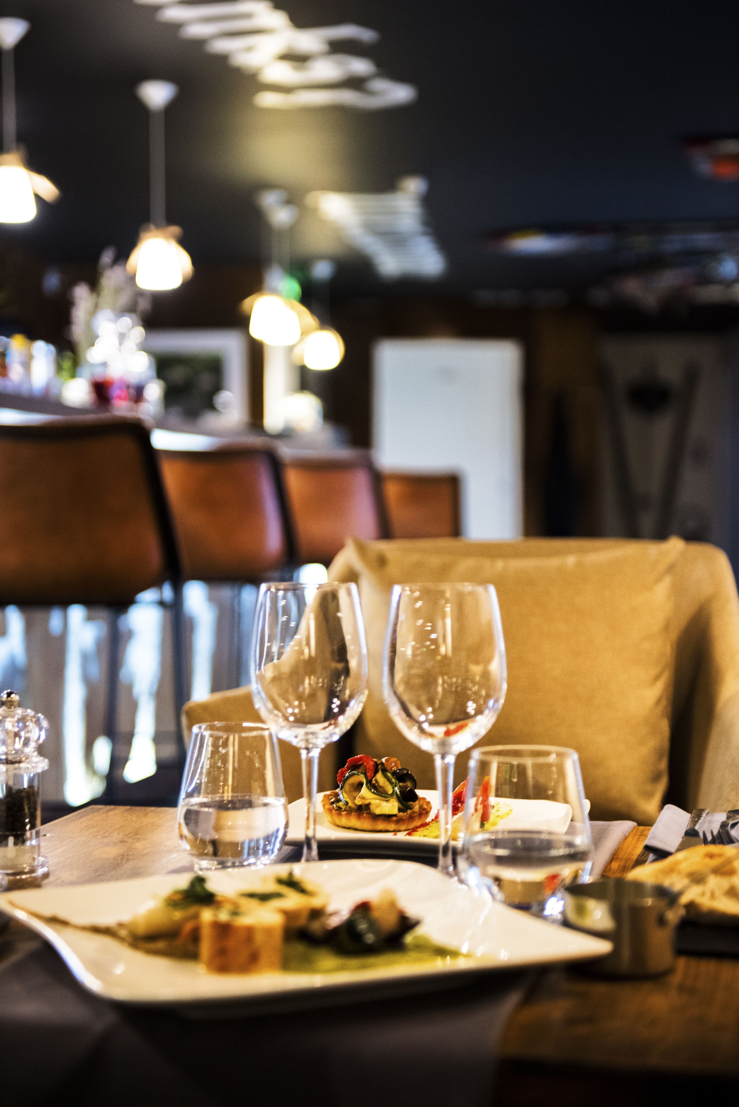 A dining table with plates of food, wine glasses, and a water glass.