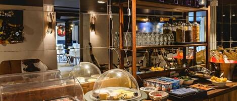 A buffet area with various food items, including a meat station, covered dishes, and a selection of beverages.