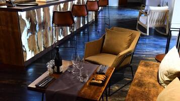 A bar area with a wooden bar counter, bar stools, and a seating area with a cushioned bench and chairs.