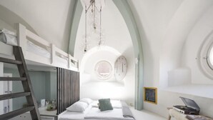 A modern bedroom with a loft bed, a desk, and a round window. - Hostel ROOM Rotterdam (Rotterdam)