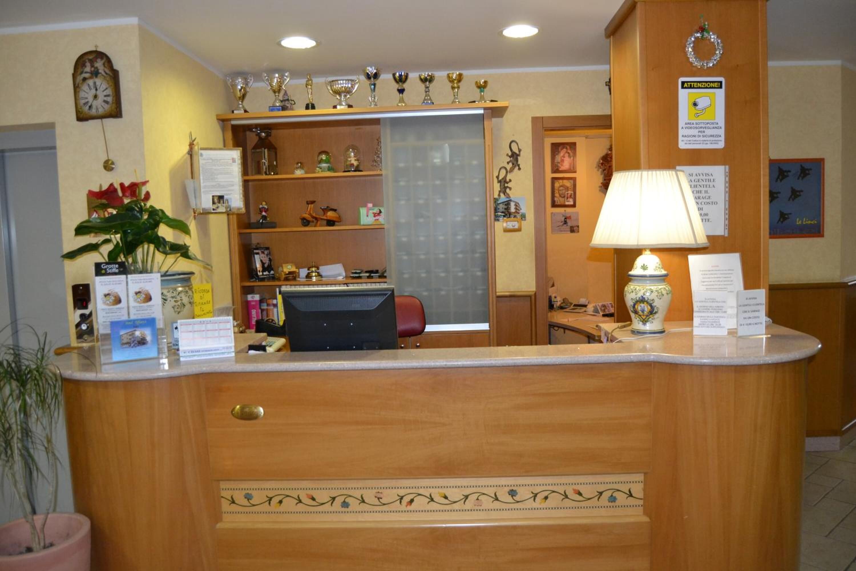 Mostrador de recepción con trofeos, un reloj y una planta en maceta.