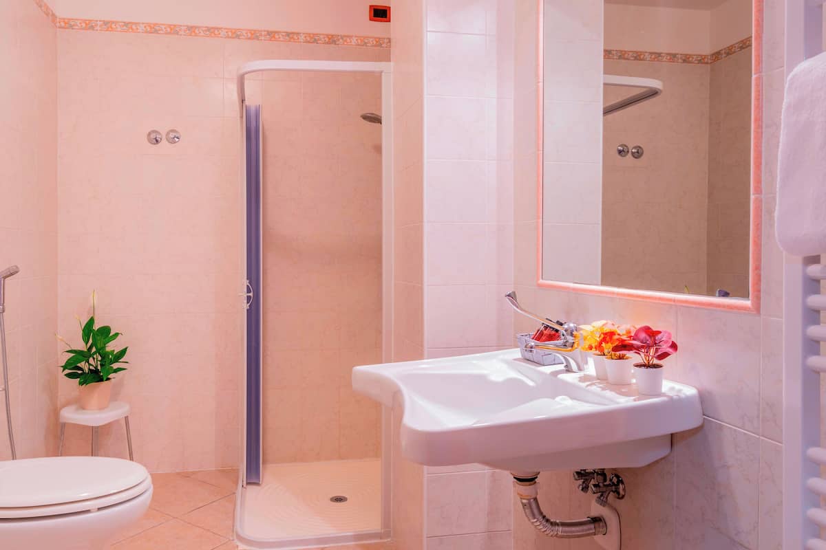 Une salle de bain équipée d’une douche, de toilettes, d’un lavabo et d’une plante en pot.