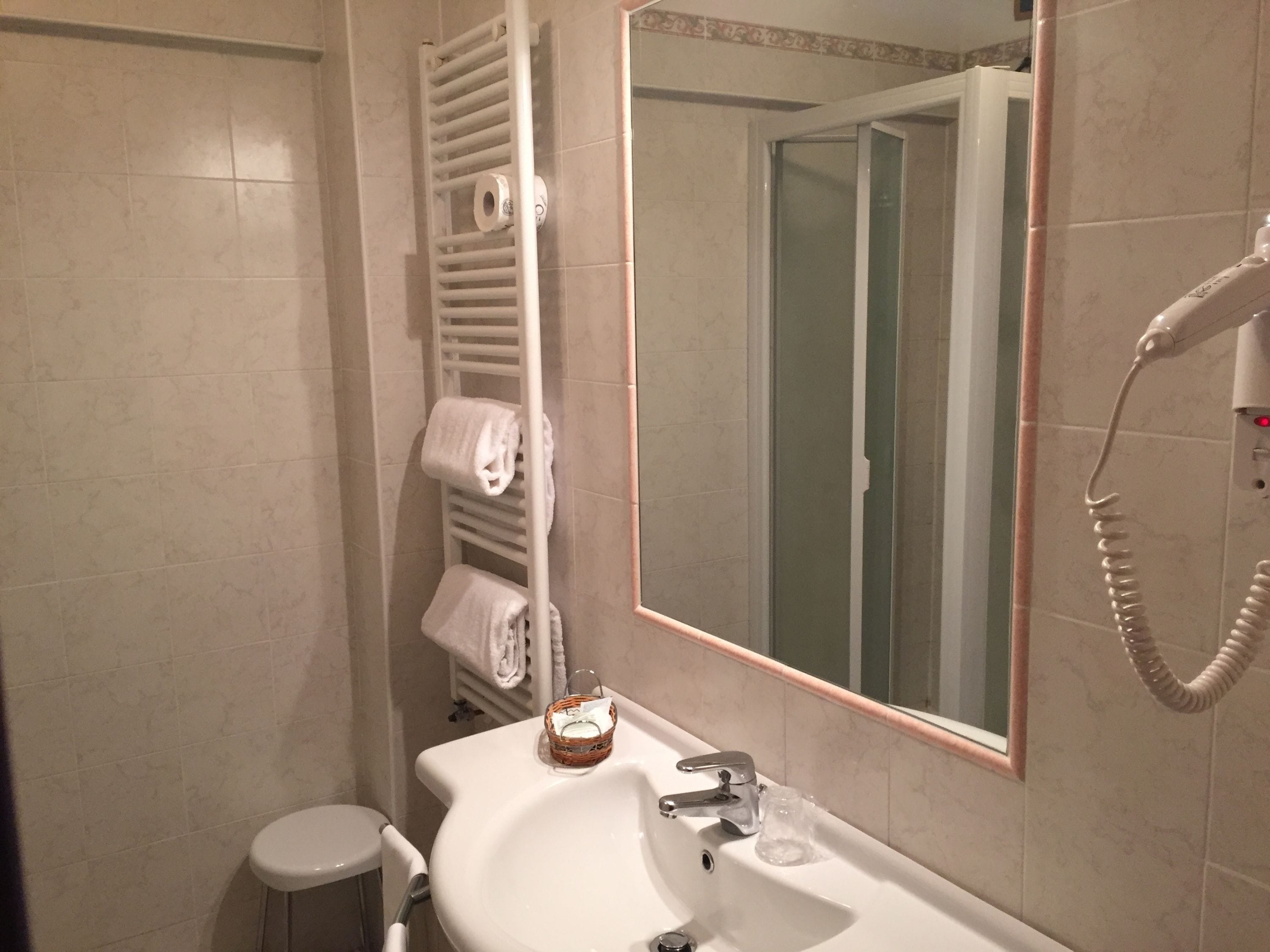A bathroom with a white sink, a mirror, a towel rack, and a hairdryer.