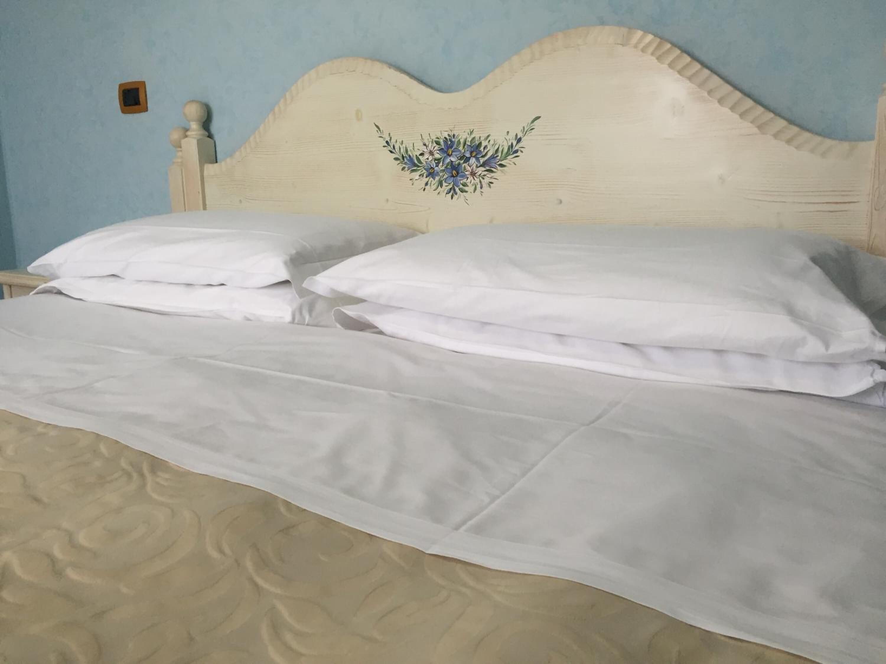 Una cama con ropa de cama blanca y un cabecero decorativo.