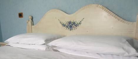 Una cama con ropa de cama blanca y un cabecero decorativo.