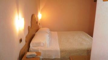 A single bed with white linens in a room with a wooden headboard and two wall-mounted lights.
