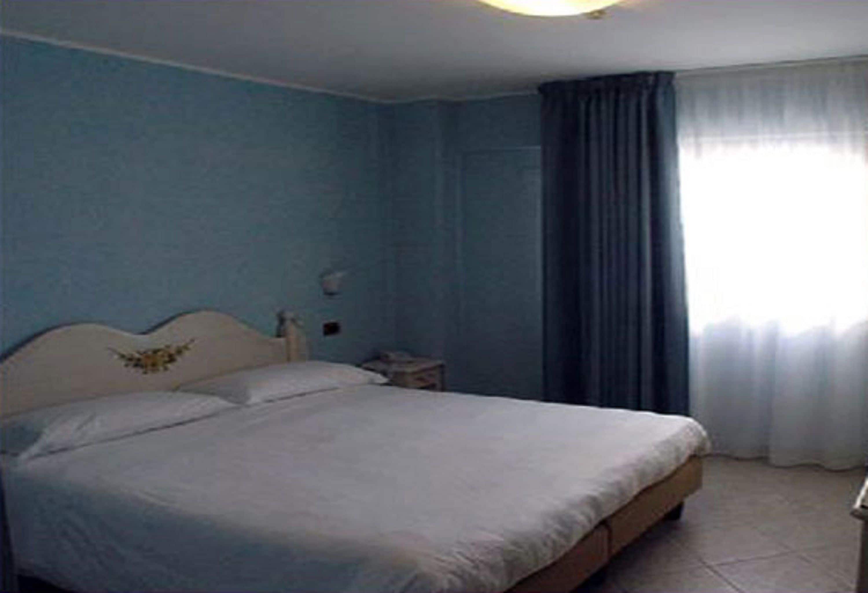 Una camera da letto con un letto, un comodino e una finestra con tende.