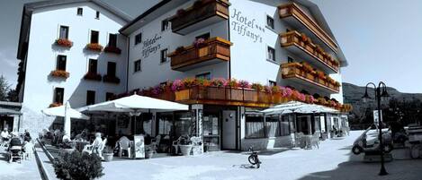 A multi-story hotel with balconies adorned with flowers, outdoor seating, and a clear view of the surrounding area.