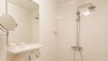 A modern bathroom with a sink, mirror, and shower.