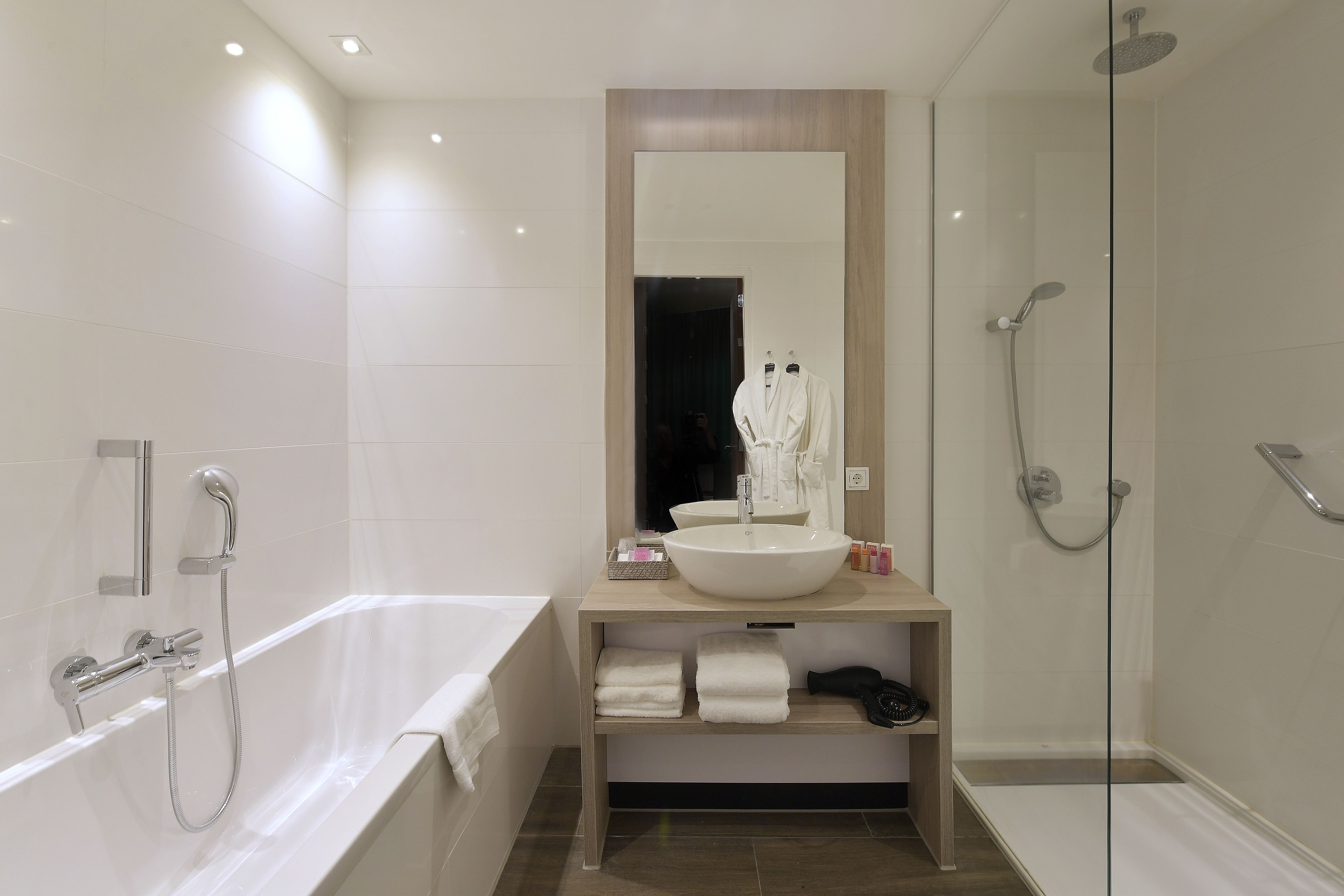 Un bagno moderno con una vasca, uno specchio grande, un lavandino e una doccia.
