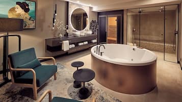 Ein modernes Badezimmer mit freistehender Badewanne, einem Waschtisch mit großem Spiegel und einer Sitzecke mit Stühlen und einem kleinen Tisch.