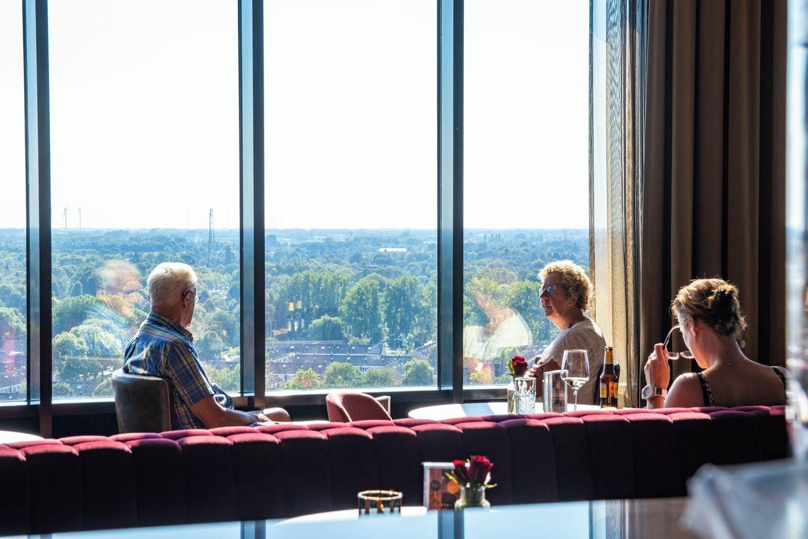 Een hotelkamer hoog in een wolkenkrabber met grote ramen en uitzicht over de stad.