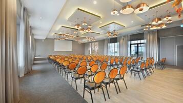 A conference room with rows of chairs, a large screen, and modern pendant lighting.