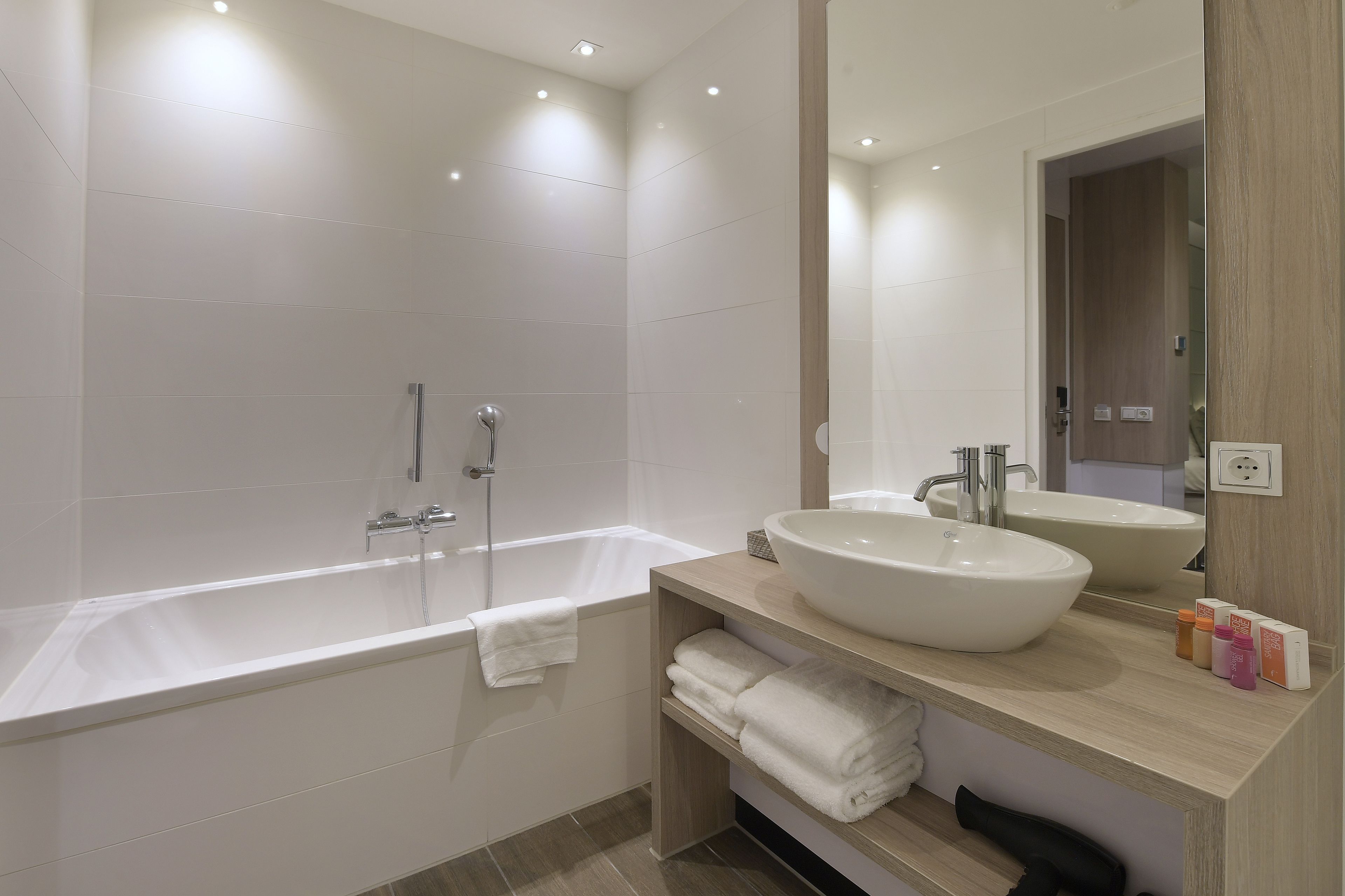 Un bagno moderno con vasca, un lavandino ampio e uno specchio. Asciugamani e articoli da toilette sono presenti sul ripiano.
