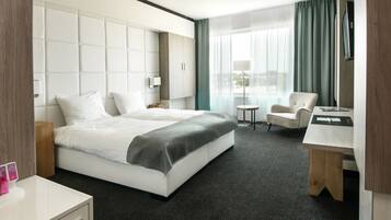 Een hotelkamer met een groot bed, een bureau, een stoel en een televisie.