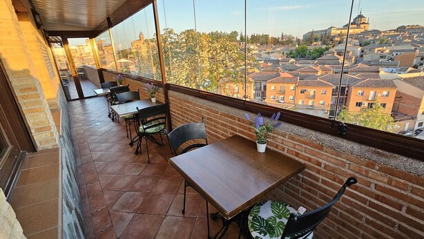 Una terraza con vistas a un paisaje urbano, con edificios de ladrillo y una estructura en forma de cúpula.