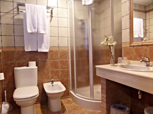 Un baño con inodoro, bidé, ducha y lavamanos.
