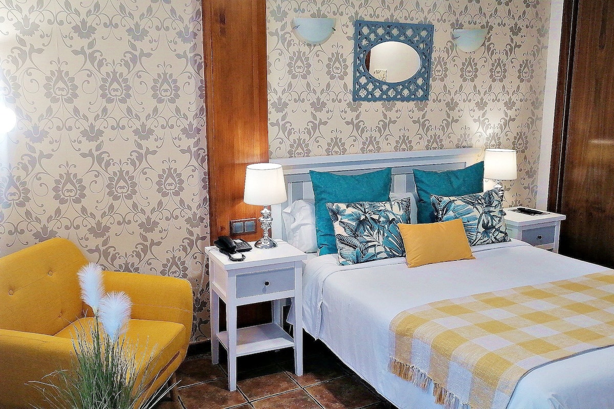 A hotel room with a bed, two nightstands, a chair, and a mirror on the wall.