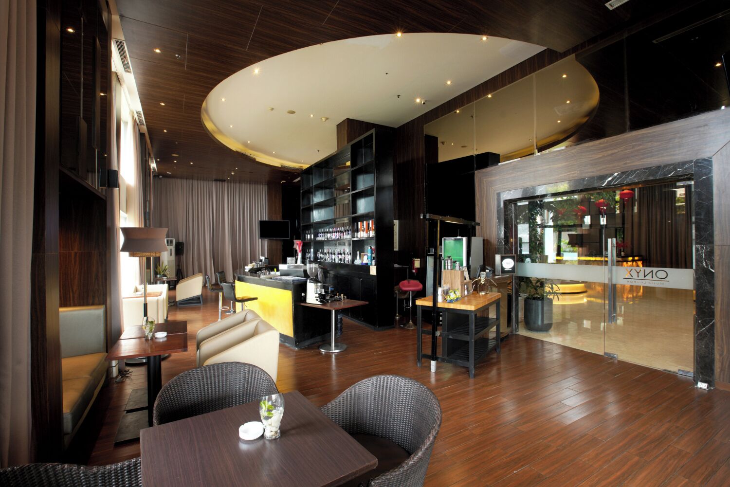 A modern hotel lobby with a bar area, seating, and a large mirror reflecting the interior.