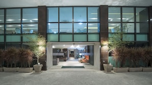 Een modern gebouw met grote glasramen, een receptie met een balie en potplanten.