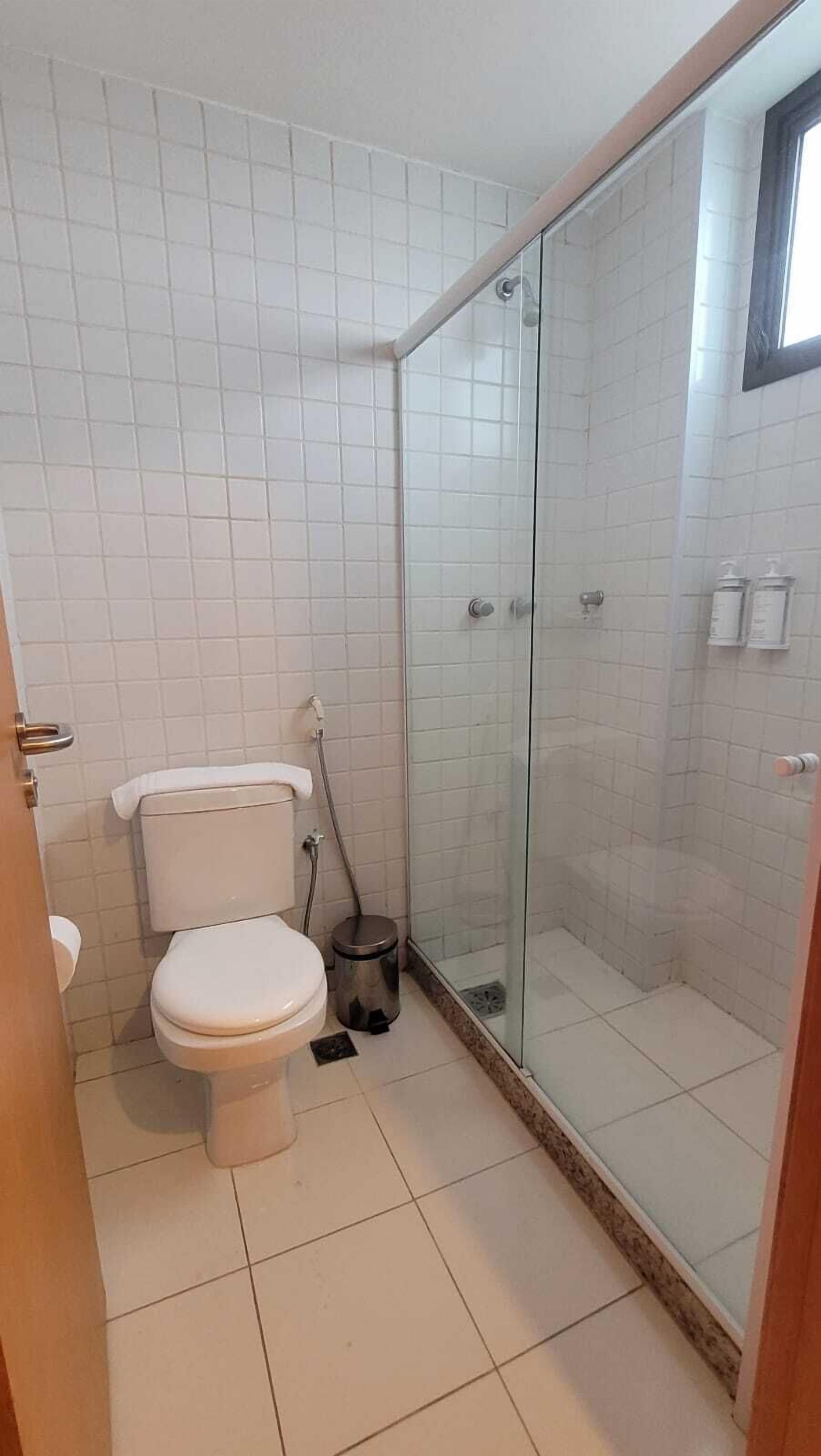 A bathroom with a toilet, a glass shower enclosure, and tiled walls.