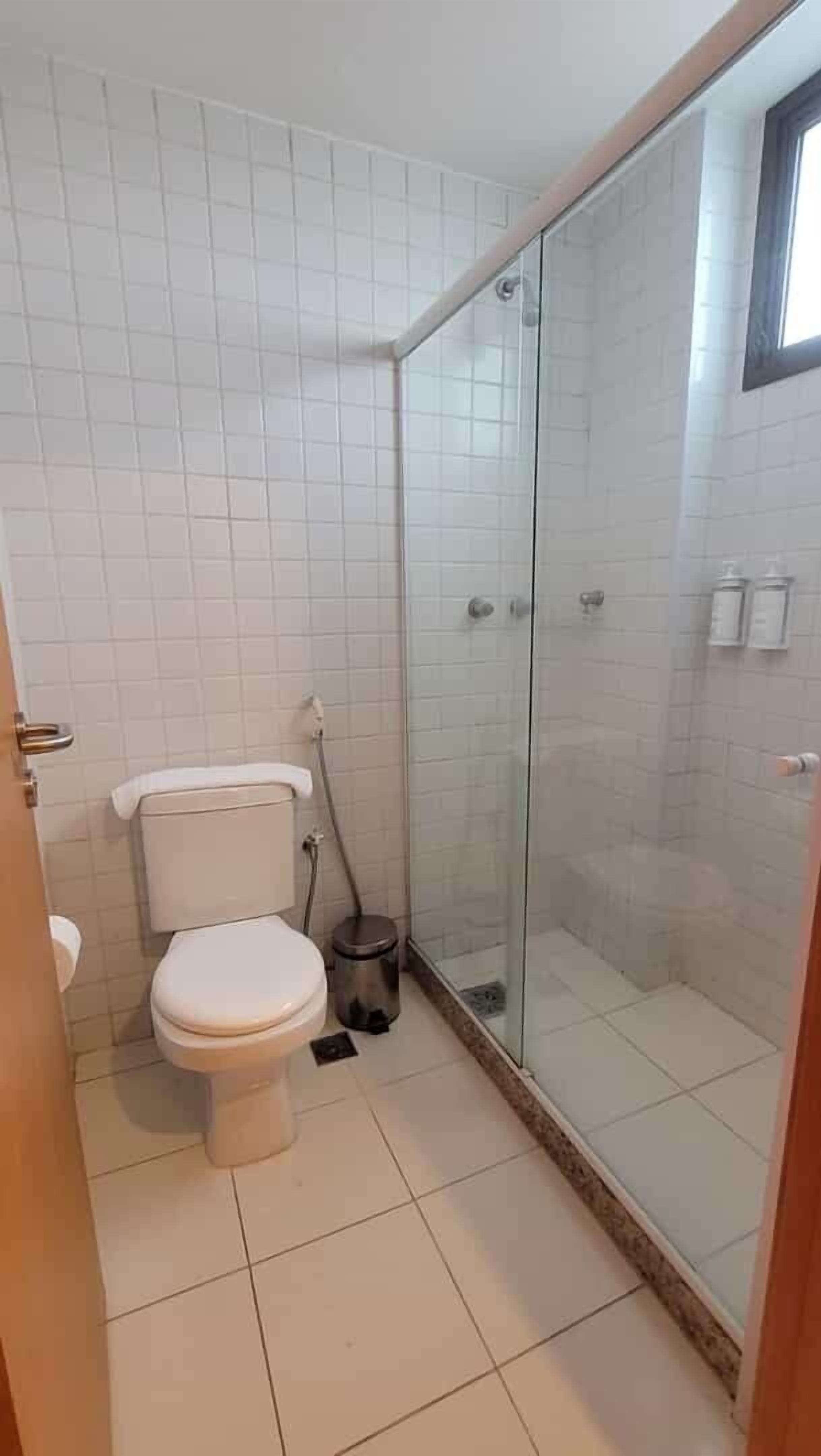 A bathroom with a toilet, a glass-enclosed shower, and tiled walls.
