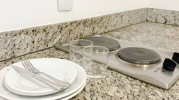 Una cocina con encimeras de granito, estufa y comedor con platos, cubiertos y vasos.
