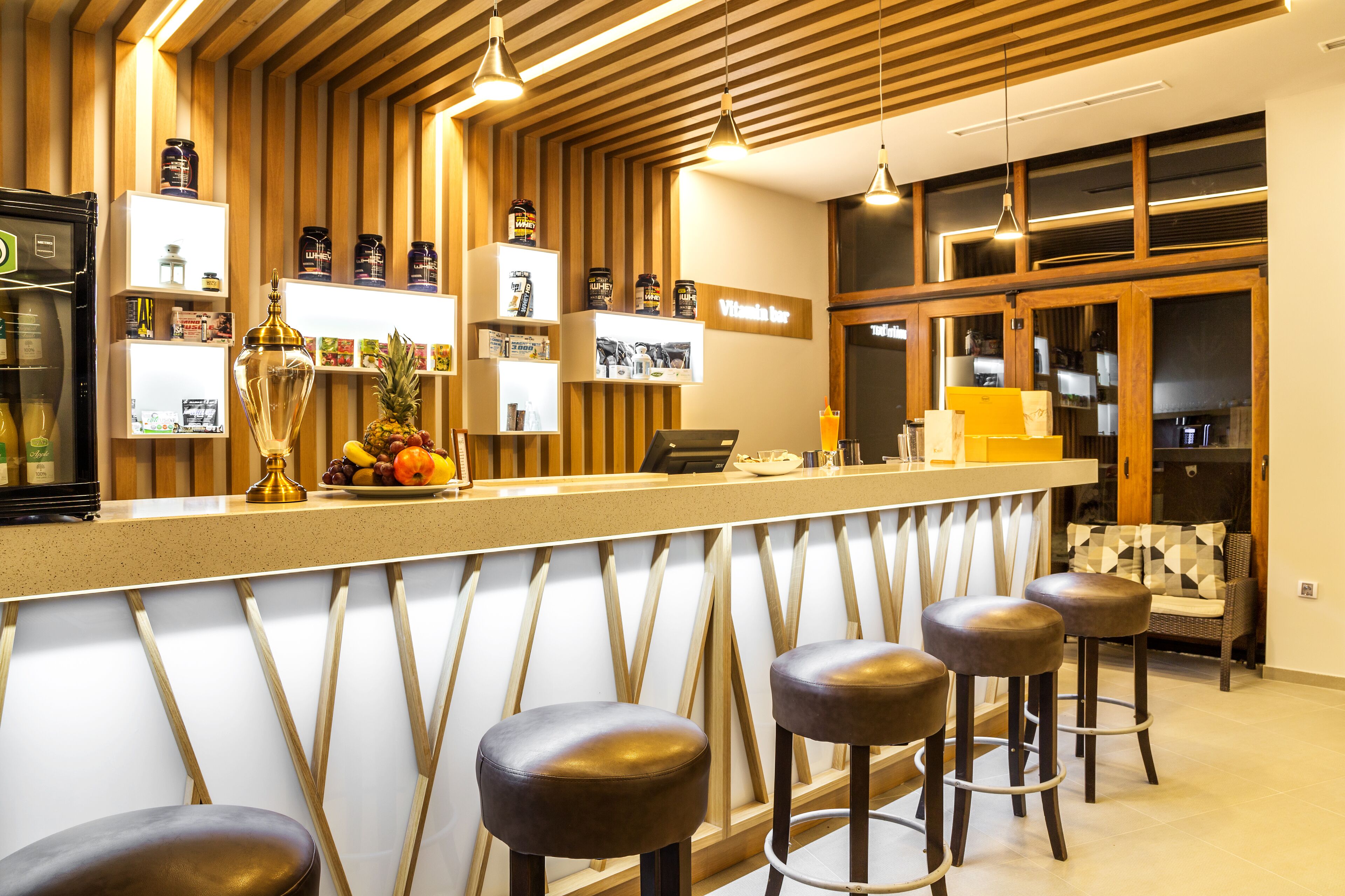 A bar area with wooden paneling, a counter with stools, and shelves with various items.